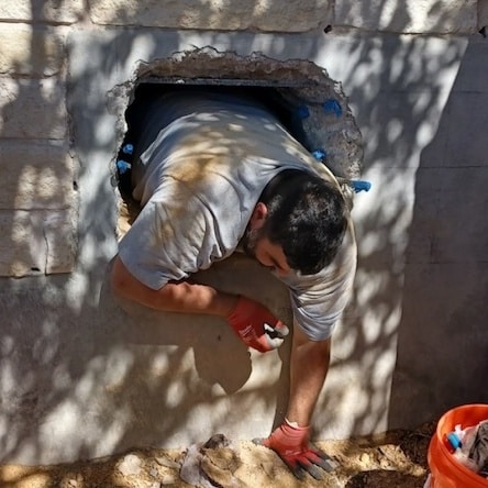 A plumber is working in a small area on a property.